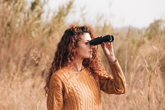 Zijdelings vrouw die door verrekijkers kijkt