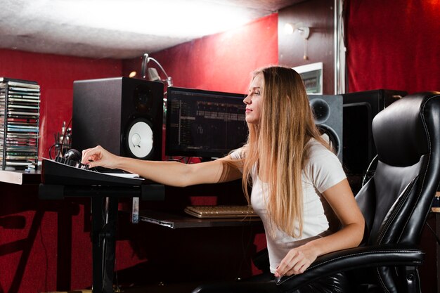 Zijdelings vrouwenzitting in een studio en het bekijken hoofdtelefoons