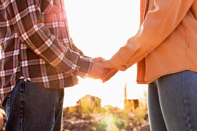 Gratis foto zijwaarts paar hand in hand bij de zonsondergang