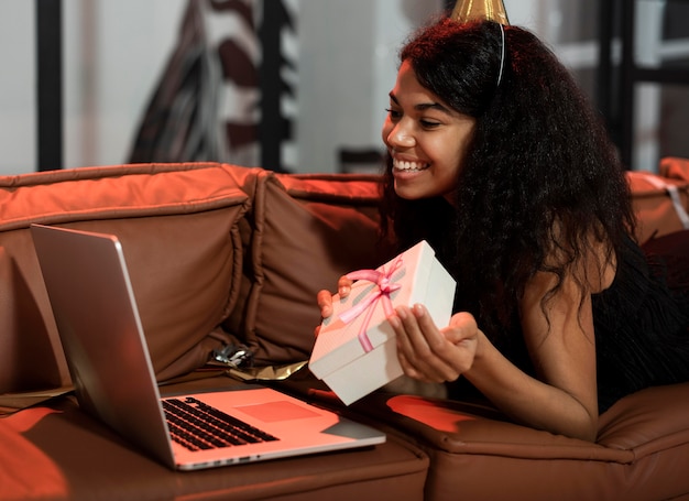 Gratis foto zijwaartse vrouw die haar cadeau laat zien tijdens een videochat op een oudejaarsfeestje