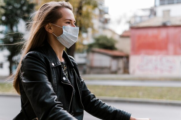 Zijwaartse vrouw die masker draagt en de fiets berijdt