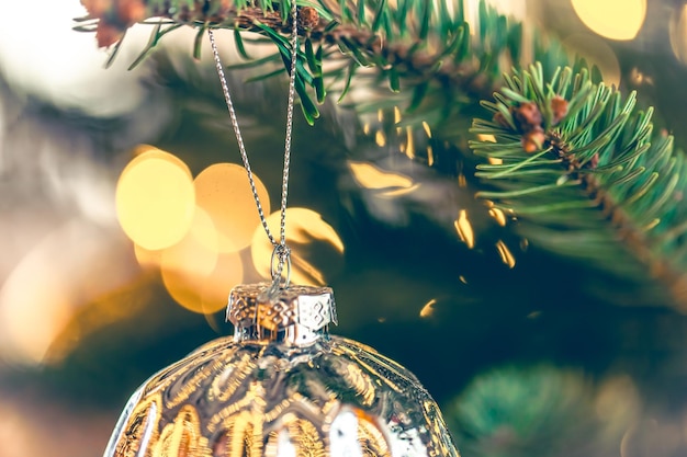 Zilveren glanzende kerstbal op een kerstboomtakclose-up