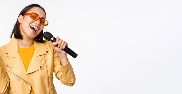 Zingen meisje met microfoon die liedjes uitvoert bij karaoke die op een witte achtergrond staat