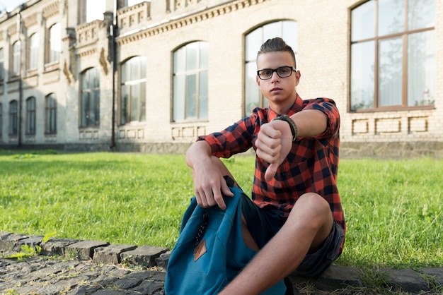 Zittend tienerschooljongen die camera het afkeuren bekijken