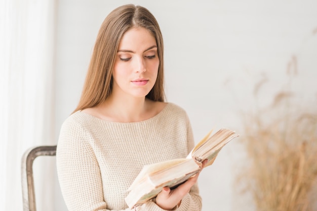 Zitting van de blonde de jonge vrouw op het boek van de stoellezing