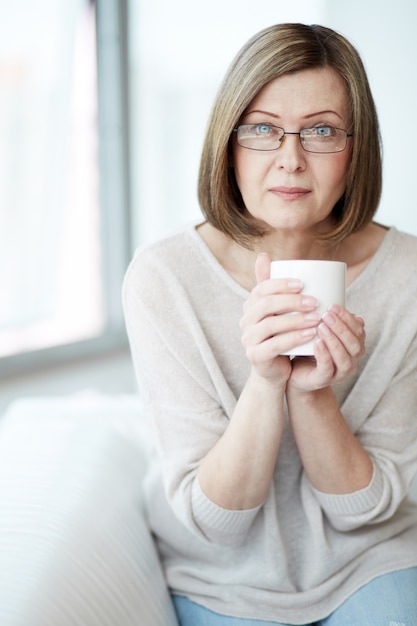 Zitting van de dame op de bank met een kopje koffie