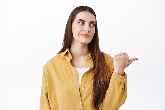 Zo lame Sceptische en teleurgestelde stijlvolle vrouw grijns wijzend en veroordelend opzij kijkend met de rechterkant teleurstellende promo-deal, een hekel aan iets dat op een witte achtergrond staat