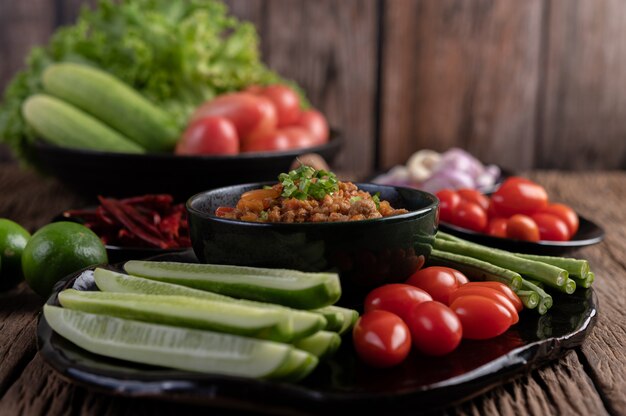 Zoet varkensvlees in een zwarte kom, compleet met komkommers, kousenband, tomaten en bijgerechten