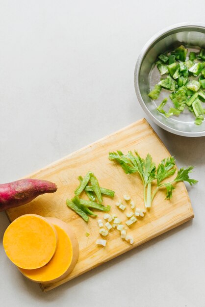 Zoete aardappel; gesneden pompoen en selderij op houten snijplank