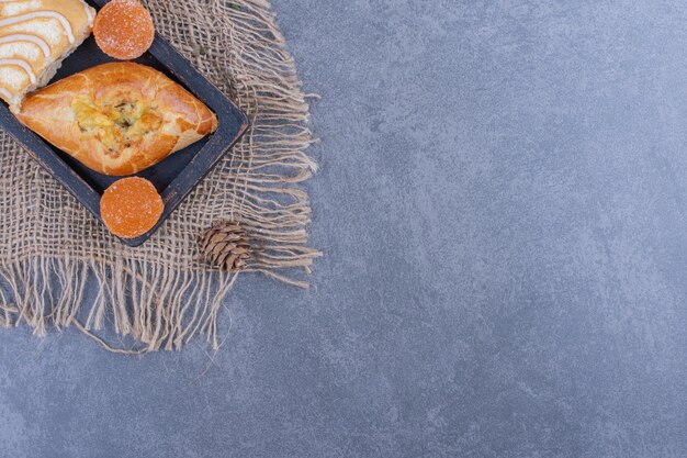 Zoete broodjescake met geleisuikergoed en dennenappels op een zak