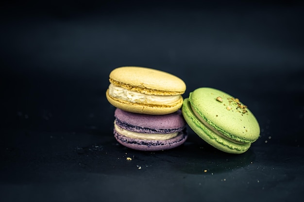 Zoete en kleurrijke Franse bitterkoekjes of macaron op zwarte achtergrond