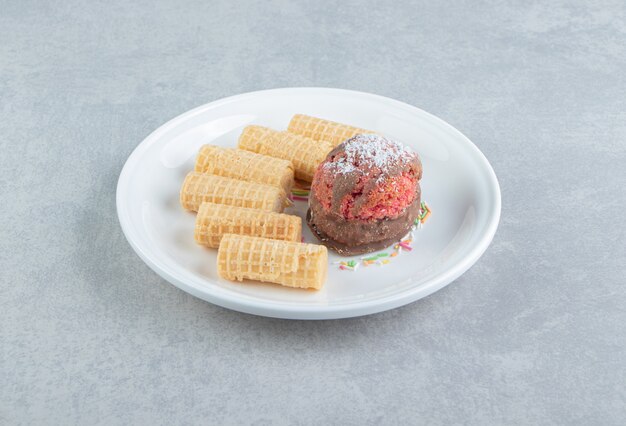 Zoete gesneden wafelrollen met cake op een witte plaat.