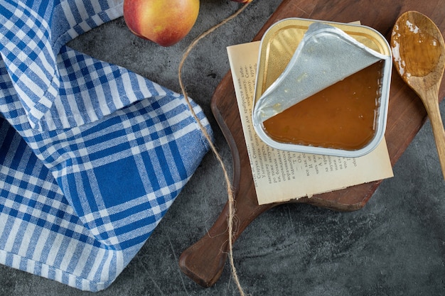 Zoete jam met perziken en houten lepel op een houten bord