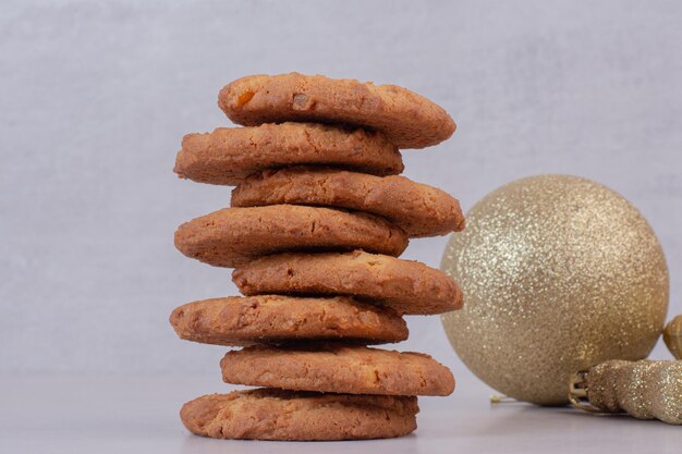 Zoete koekjes met gouden kerstballen op witte tafel.