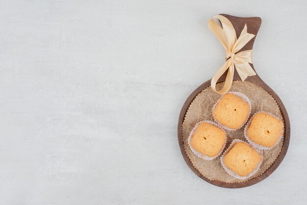 Zoete koekjes met room op houten plaat die met lint wordt verfraaid.