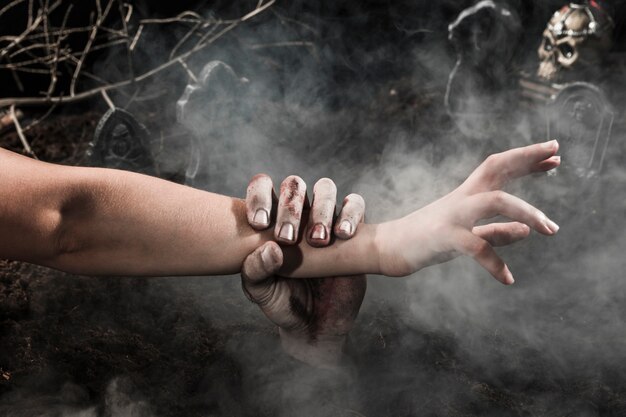 Zombie hand vangen persoon bij Halloween begraafplaats