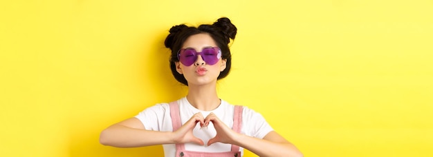 Zomer- en modeconcept schattig glamoureus meisje met zonnebril en haarknots met hartteken en tuit