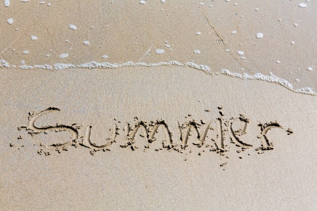 Zomer met de hand geschreven inschrijving in zand op een strand