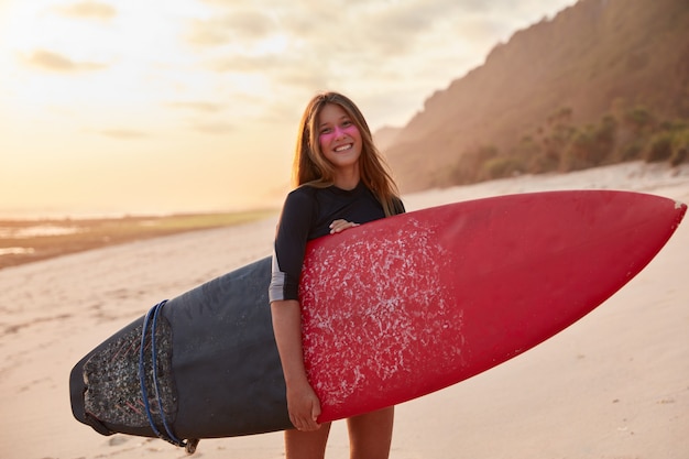 Gratis foto zomeractiviteiten concept. tevreden mooie jonge vrouw gekleed in zwembroek, draagt lang bord, heeft vakantie in het buitenland in het resortland