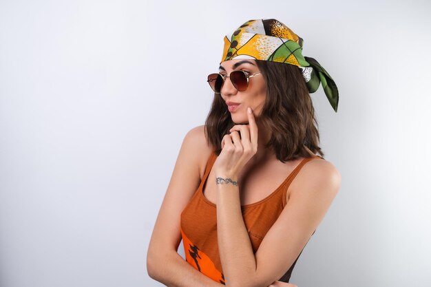 Zomerportret van een jonge vrouw in een sportbadpak met hoofddoek en zonnebril