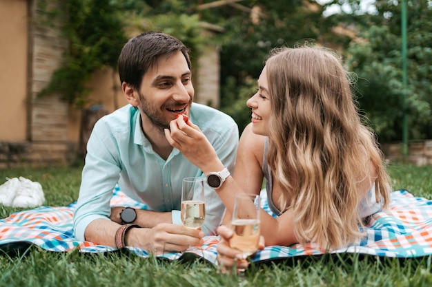 Zomervakantie, mensen, romantiek, man en vrouw die elkaar aardbeien voeren terwijl ze thuis bruisend drinken en samen genieten