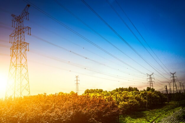 Zon instelling achter het silhouet van elektriciteitspylonen