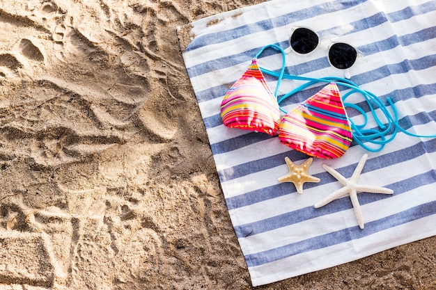 Zonnebril, zwempak en zeester op strandhanddoek op zandig strand