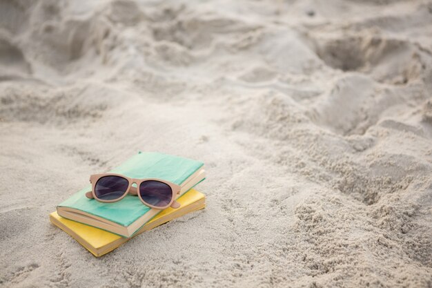 Zonnebrillen en boeken op zand