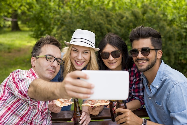 Zonnig landschap van een groep blanke vrienden die roosteren met hun bierflesjes in een park