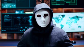 Gratis foto zoom in op cybercrimineel die een wit masker draagt en naar de camera kijkt.