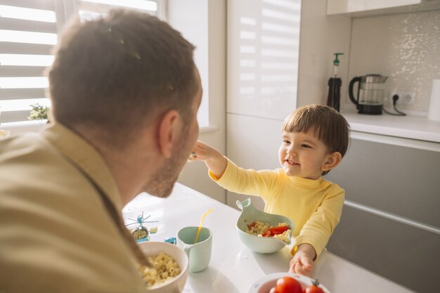 Zoon die zijn vader in de keuken voedt