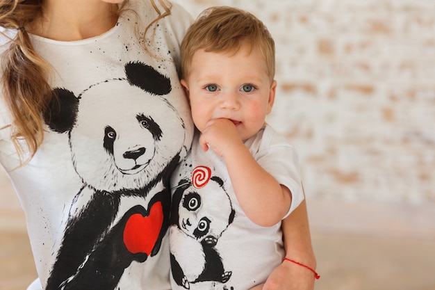 Zoontje in de handen van de moeder. Familylook van t-shirts met panda&#39;s