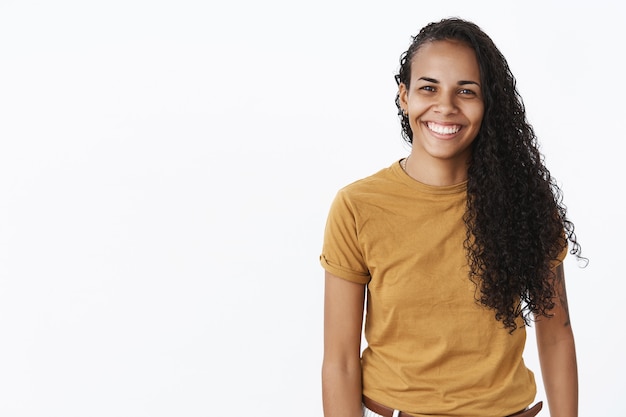 Zorgeloos gelukkig afro-amerikaanse vrouw glimlachend in grote lijnen op witte achtergrond