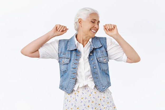 Zorgeloos gelukkig levendige vrolijke senior vrouw met grijze hai handen opsteken vuist pomp of stretching gevoel vrolijk en vrolijk genieten van gezond leiden actieve levensstijl witte achtergrond