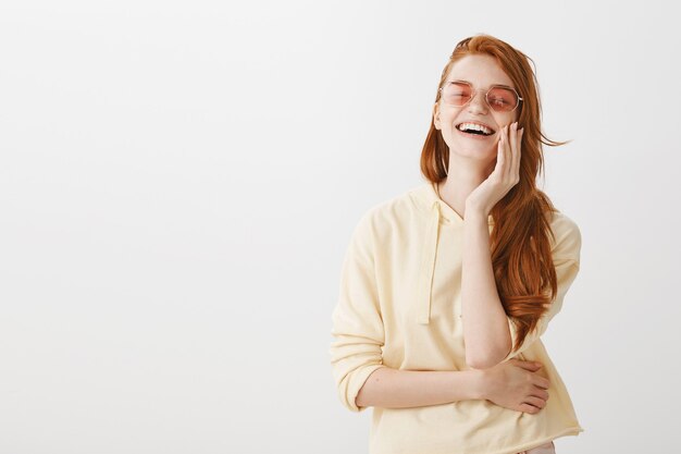 Zorgeloos gember meisje in zonnebril lachen van geluk
