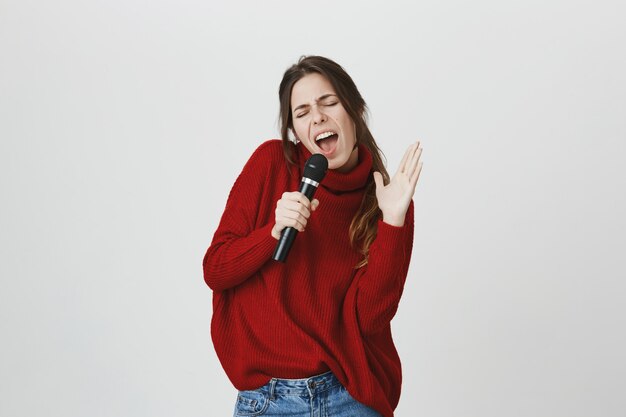 Zorgeloos vrouw plezier karaoke, zingen in de microfoon