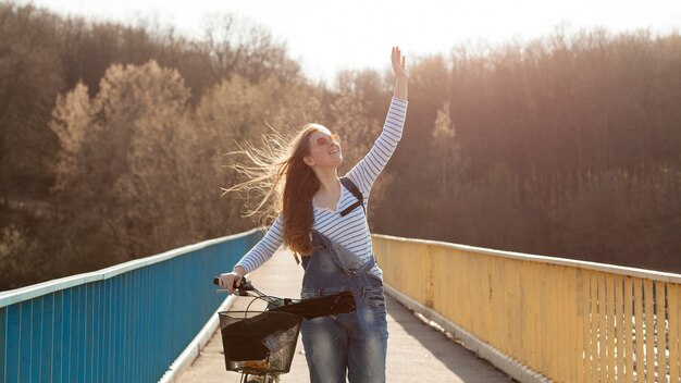 Zorgeloos vrouw poseren met fiets op brug