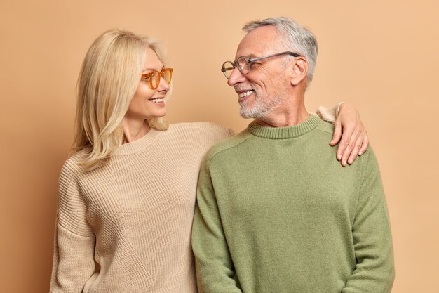 Zorgzame vrouw van middelbare leeftijd omarmt haar man kijkt met liefde en een brede glimlach