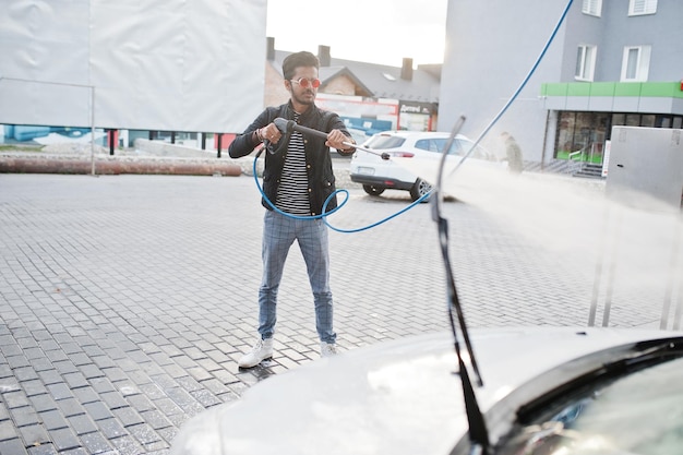 Zuid-Aziatische man of Indiase man die zijn witte transport op autowasserette wast