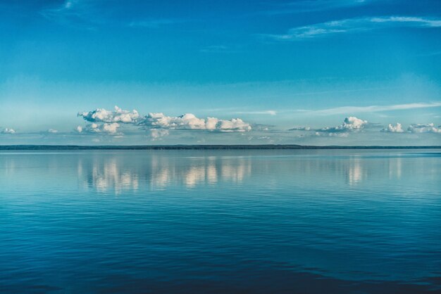 Zuivere witte wolken aan de hemel weerspiegeld in het water van de zee
