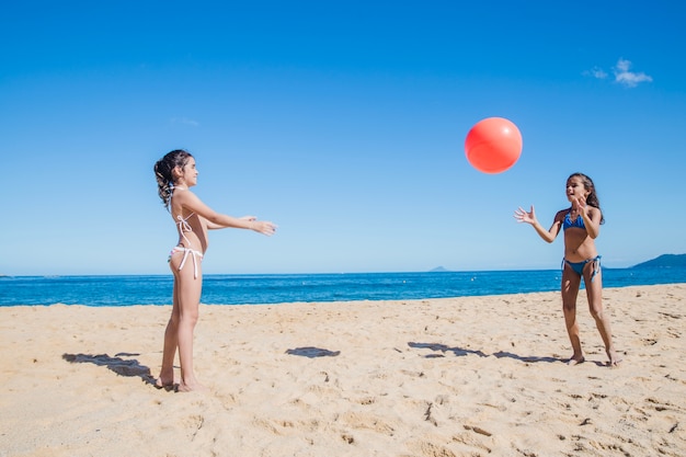Zusters spelen met bal op het strand
