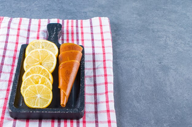 Zuur en snijd citroen op een plank op de theedoek op het marmeren oppervlak