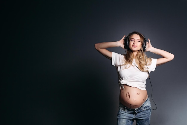 Zwangere vrouw danst en lacht met gesloten ogen