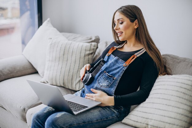 Zwangere vrouw die computer thuis gebruikt