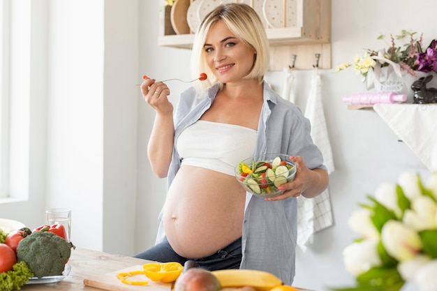 Gratis foto zwangere vrouw die de camera in de keuken bekijkt