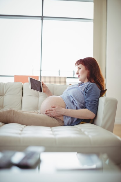 Zwangere vrouw die een echografie op digitale tafel bekijkt