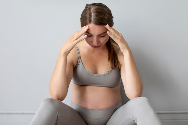 Gratis foto zwangere vrouw die een pauze neemt van thuis sporten