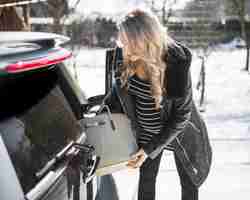 Gratis foto zwangere vrouw die handtas van auto neemt