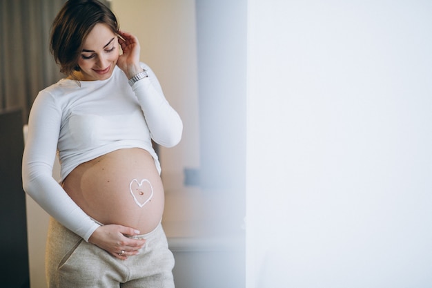 Zwangere vrouw die room op de buik toepast om uitrekken te voorkomen