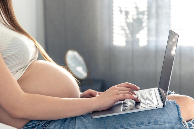 Gratis foto zwangere vrouw in bed in kamer interieur met laptop